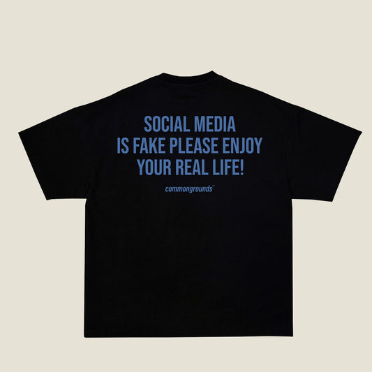SOCIAL MEDIA IS FAKE PLEASE ENJOY YOUR REAL LIFE Tee in black, back print